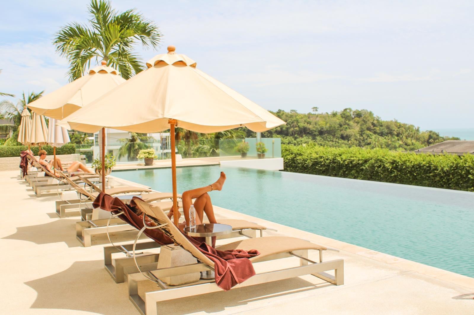 Sun loungers and parasols along the infinity pool, the sea beyond