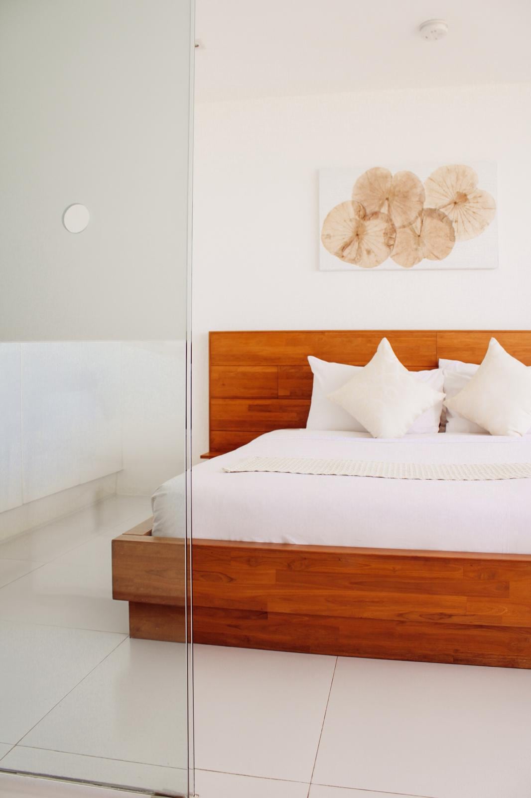 A suite bedroom at CODE, solid teak bed beside the glass-walled bathroom